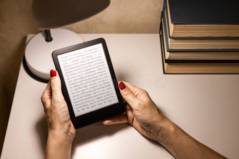 Handen houden een e-reader met tekst naast een stapel boeken vast