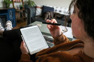 Persoon leest op een tablet en houdt een styluspen vast